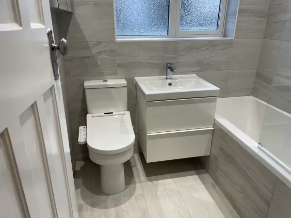 Grey tiled family bathroom with bath, vanity and toilet