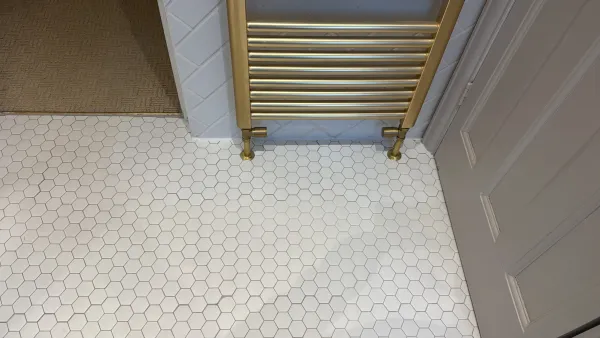 Repaired and retiled floor beneath the brass towel rail