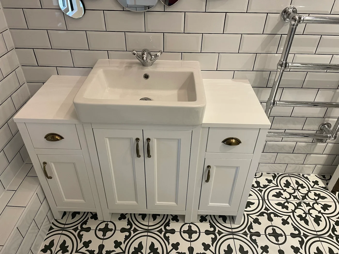 Traditional white vanity above patterned floor tiles