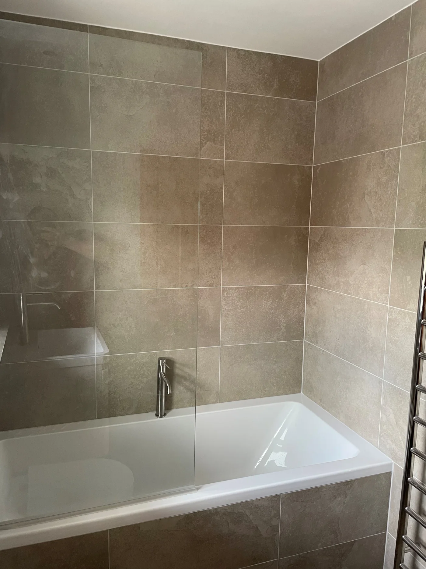 White bath with stone-effect tiled walls