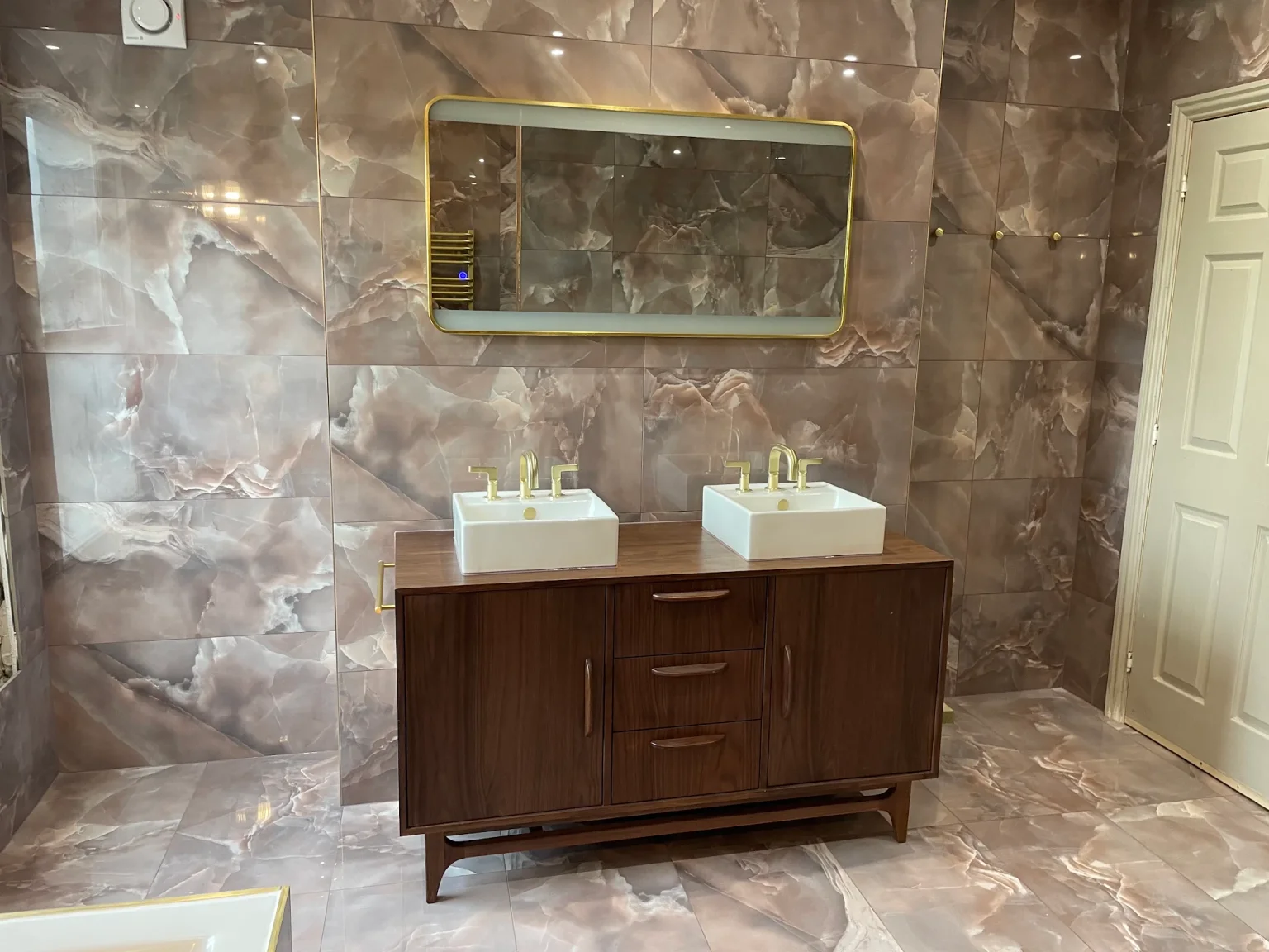 Completed client bathroom with brown marble, a timber double vanity and illuminated mirror