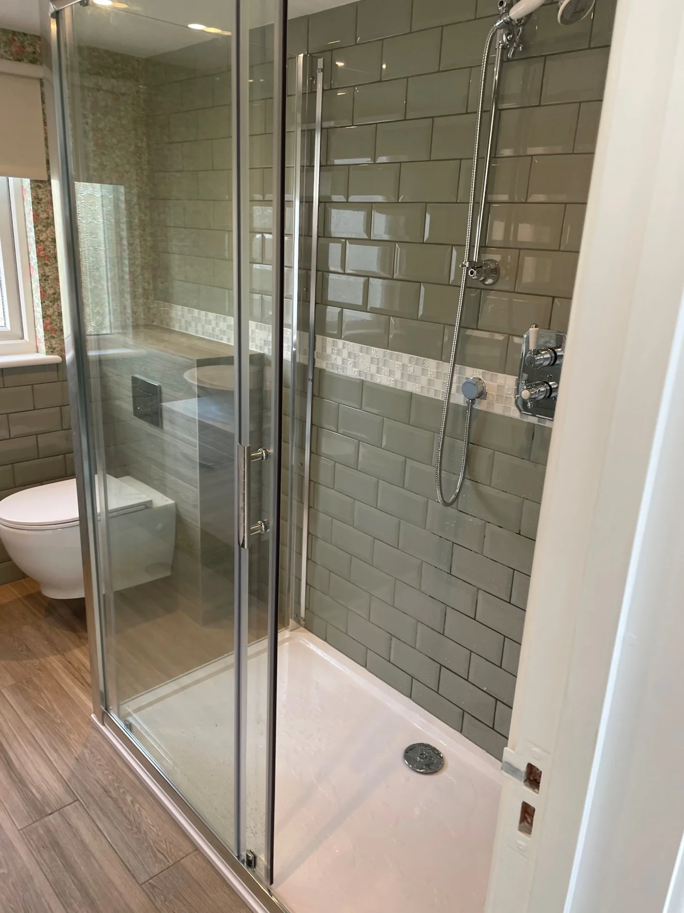 Green tiled shower room with a clear glass enclosure