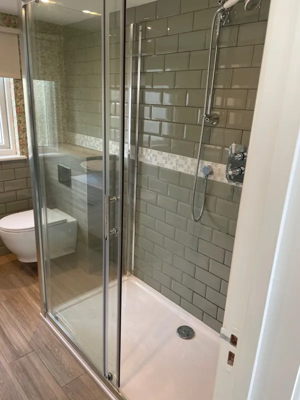 Green tiled shower room with a clear glass enclosure