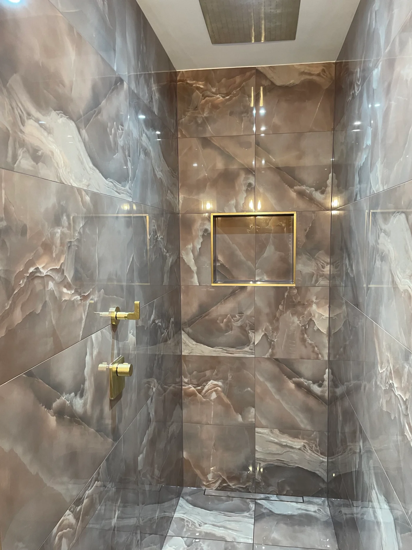 Brass-trimmed shower niche and marble-effect tiling