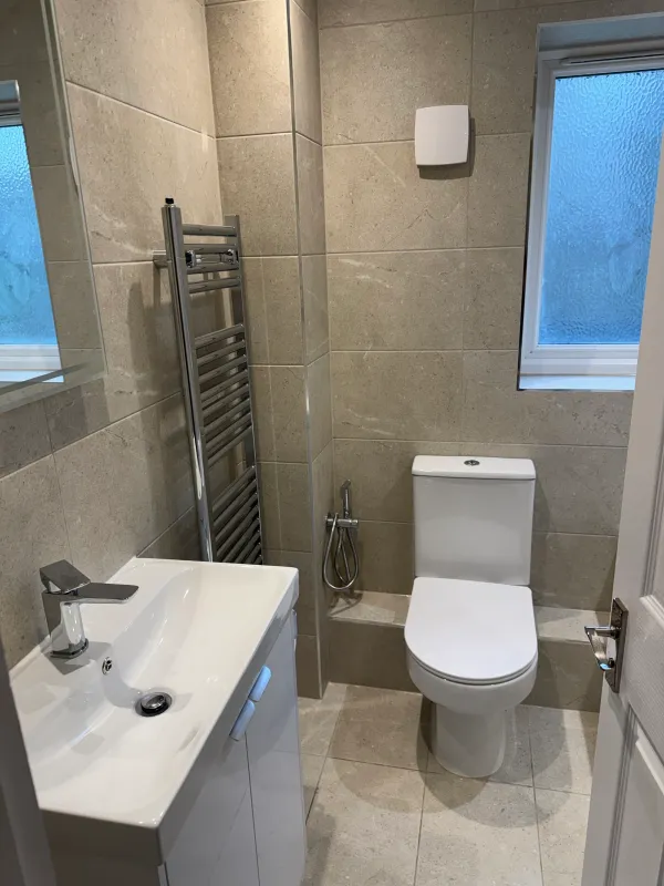Light tiled bathroom with a fitted white vanity and toilet